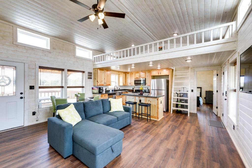 a living room with a blue couch and a kitchen at Cozy Texas Retreat with Covered Deck and Private Pond! in Lexington