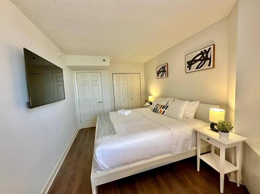 a white bedroom with a large bed and a television at Incredible Apartment with Rooftop in Pentagon City in Arlington