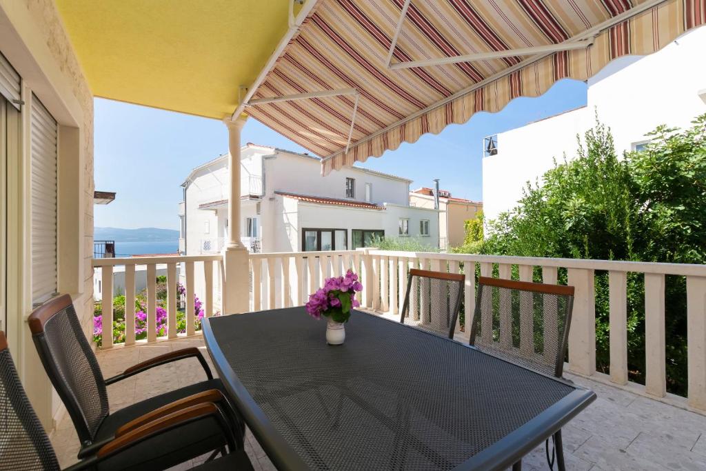 a black table on a balcony with a vase of flowers at Apartment Jele in Omiš