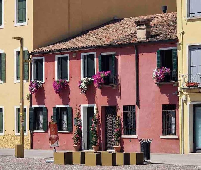 a pink building with flowers in the windows at Storico alloggio fronte piazza in Borgo Portello in Padova