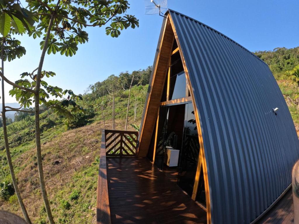 a small house with a blue roof and a wooden walkway at chalé bella vista in Massaranduba
