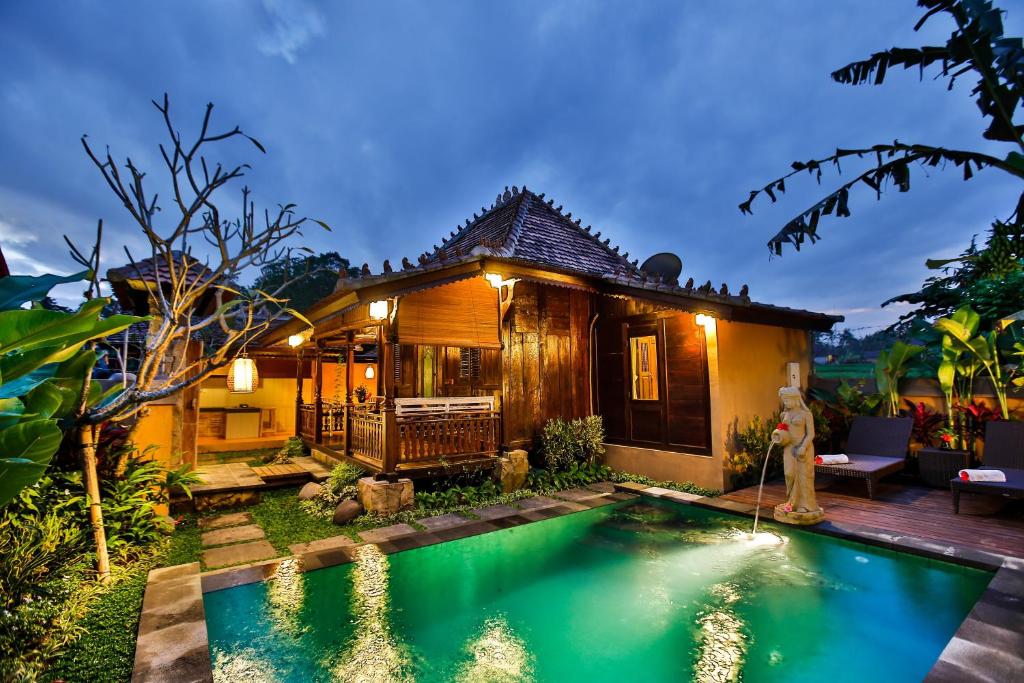 a villa with a pool in front of a house at Villa Nini in Ubud