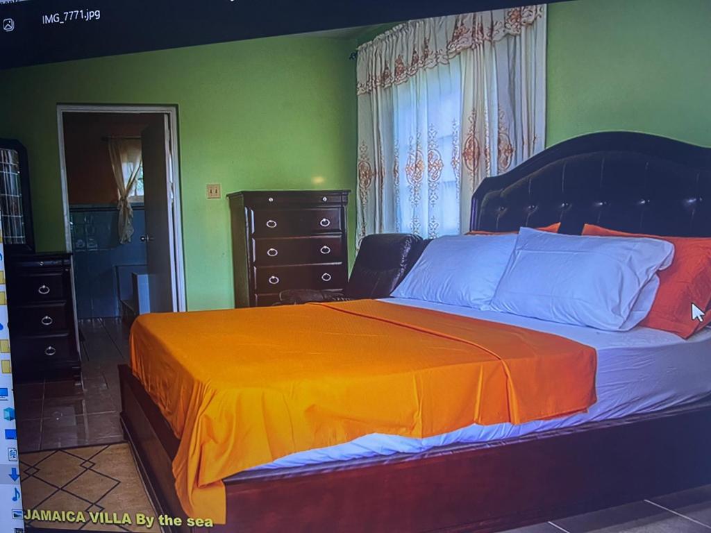 1 dormitorio con 1 cama grande con manta naranja en Jamaica Villa By The Sea, en Saint Mary
