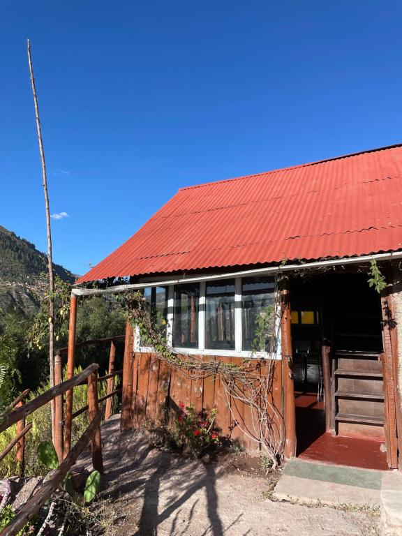 クスコにあるEcolodge las tunasの赤い屋根と柵のある家
