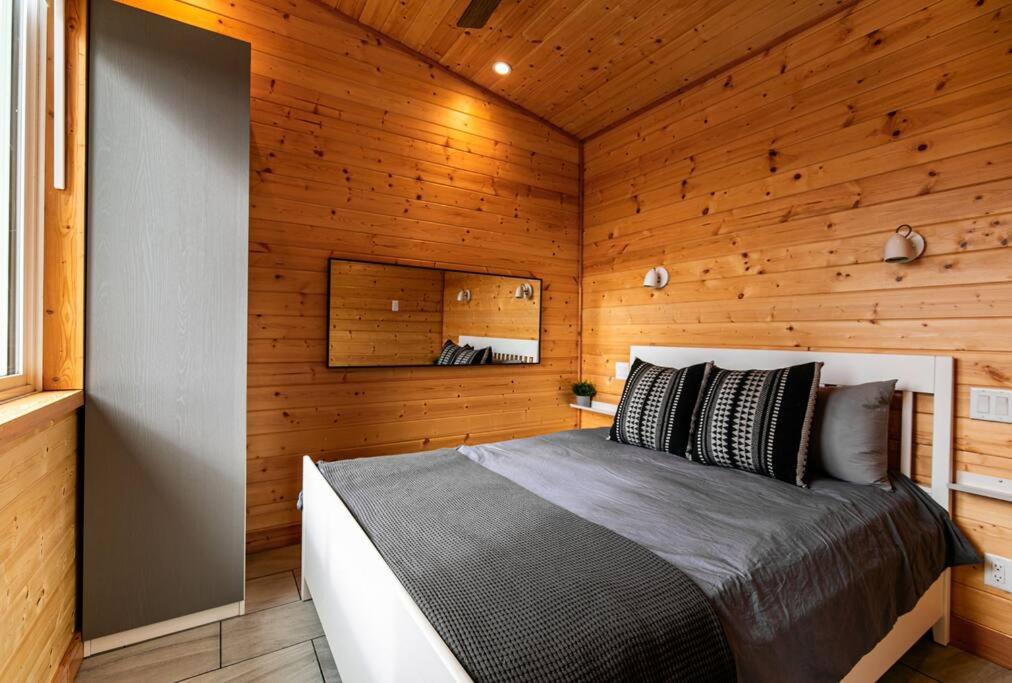 1 dormitorio con 1 cama en una cabaña de madera en 1-bedroom knotty Pine cabin w sauna & jacuzzi, en Sooke