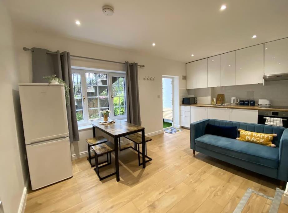 uma sala de estar com um sofá azul e uma mesa em Redhill Town Centre Garden Flat em Redhill