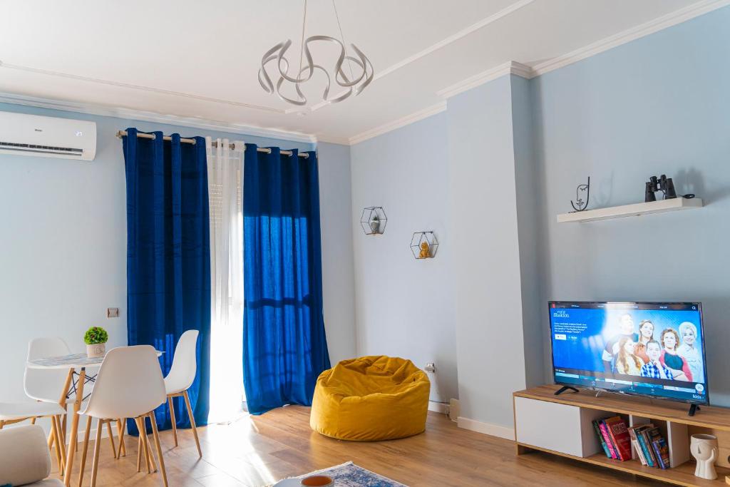 een woonkamer met blauwe gordijnen en een televisie bij Cane Apartment New Bazaar in Tirana