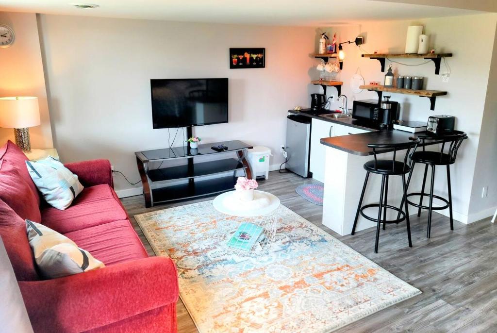 a living room with a red couch and a kitchen at Cozy Private Suite in Winnipeg