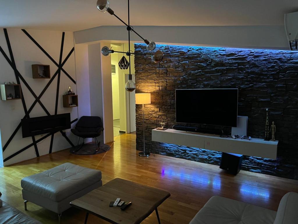 - un salon avec une télévision et un mur en pierre dans l'établissement Lusso Apartment, à Skopje