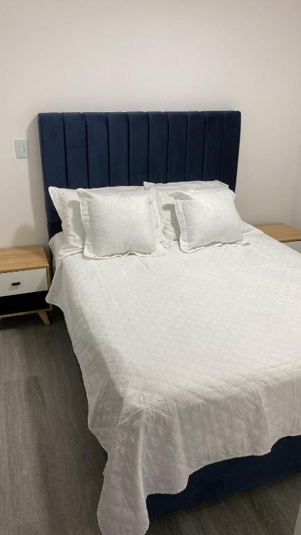 uma cama grande com uma cabeceira azul e almofadas brancas em Hermoso y acogedor apartamento em Dosquebradas