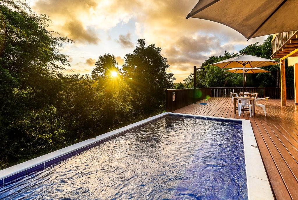 een zwembad met een tafel en een parasol bij Sítio de Praia in Arraial d'Ajuda