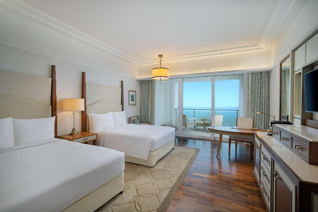 a large hotel room with two beds and a desk at Waldorf Astoria Dubai Palm Jumeirah in Dubai