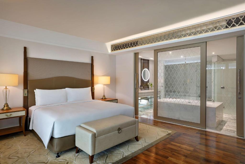 a bedroom with a large bed and a bathroom at Waldorf Astoria Dubai Palm Jumeirah in Dubai