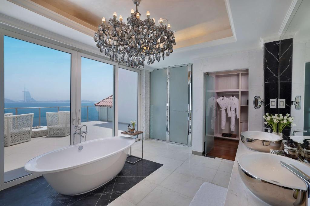 a bathroom with a tub and two sinks and a chandelier at Waldorf Astoria Dubai Palm Jumeirah in Dubai