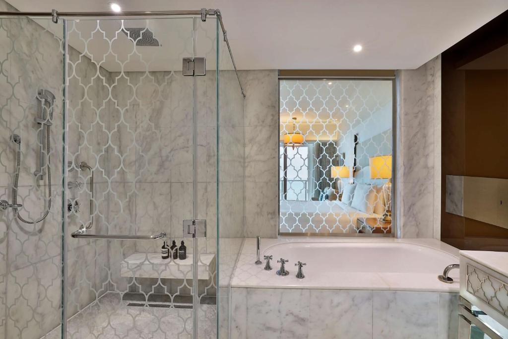a bathroom with a tub and a glass shower at Waldorf Astoria Dubai Palm Jumeirah in Dubai