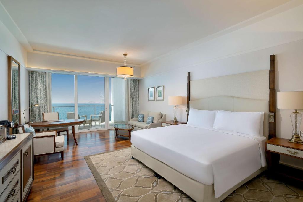 a bedroom with a large white bed and a living room at Waldorf Astoria Dubai Palm Jumeirah in Dubai