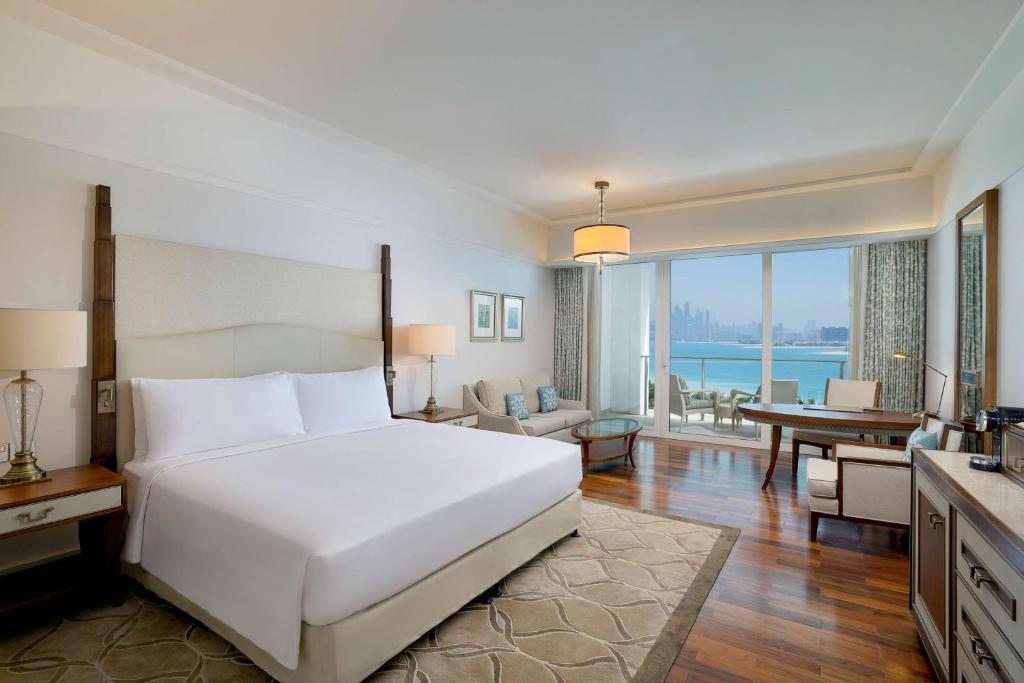 a bedroom with a large white bed and a desk at Waldorf Astoria Dubai Palm Jumeirah in Dubai