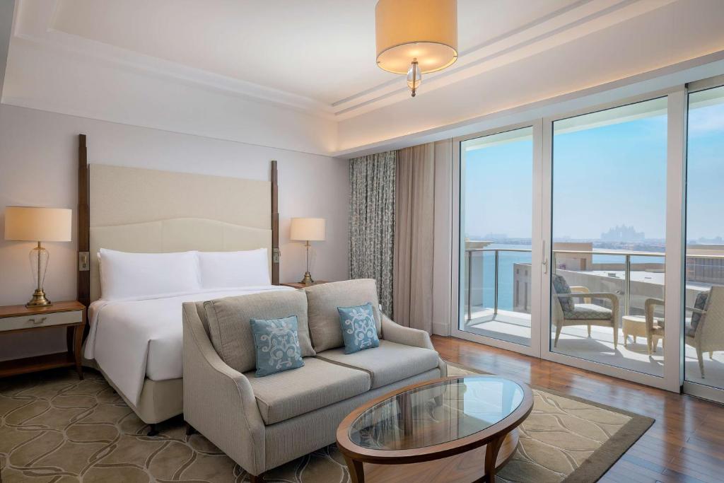 a hotel room with a bed and a couch and a window at Waldorf Astoria Dubai Palm Jumeirah in Dubai