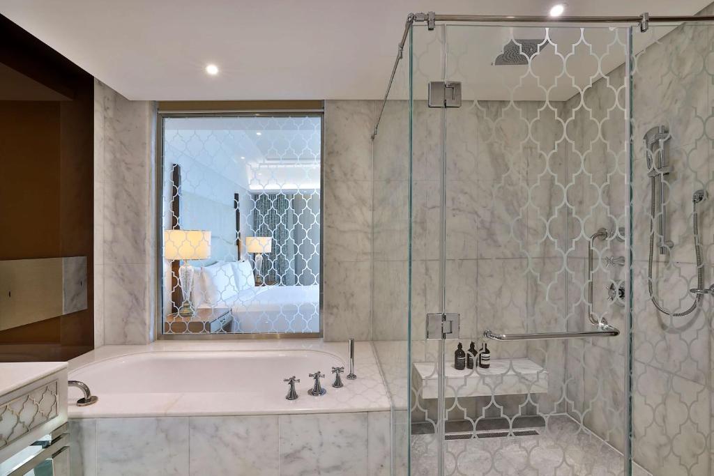 a bathroom with a tub and a glass shower at Waldorf Astoria Dubai Palm Jumeirah in Dubai