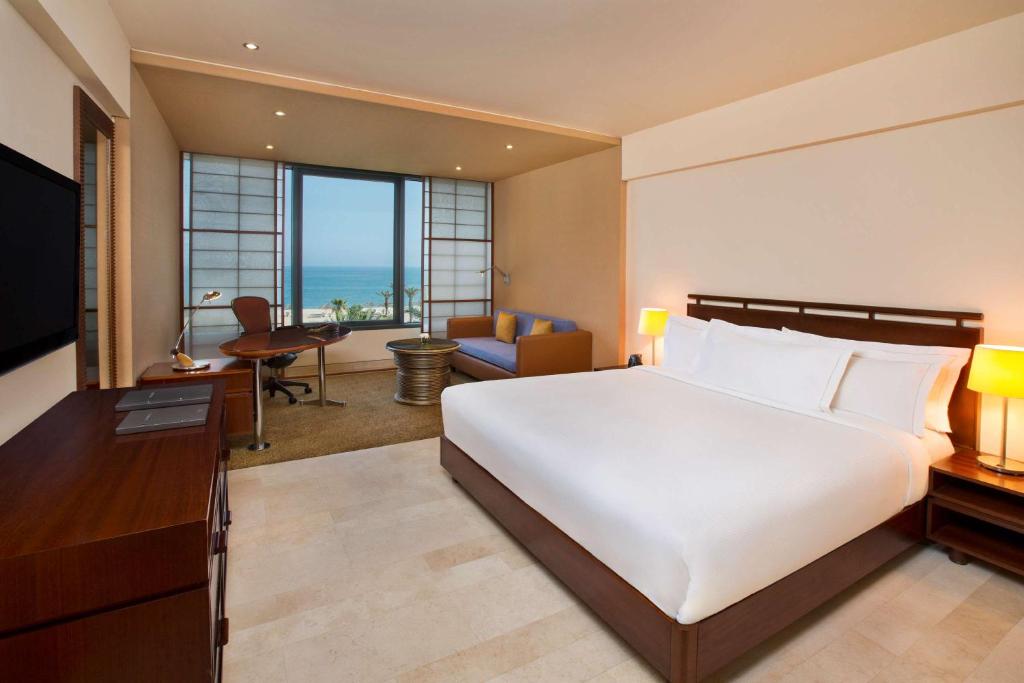 a bedroom with a large bed and a living room at Hilton Kuwait Resort in Kuwait