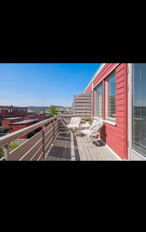 a red house with two chairs on a deck at Rekkehus i Trondheim, gratis parkering in Trondheim