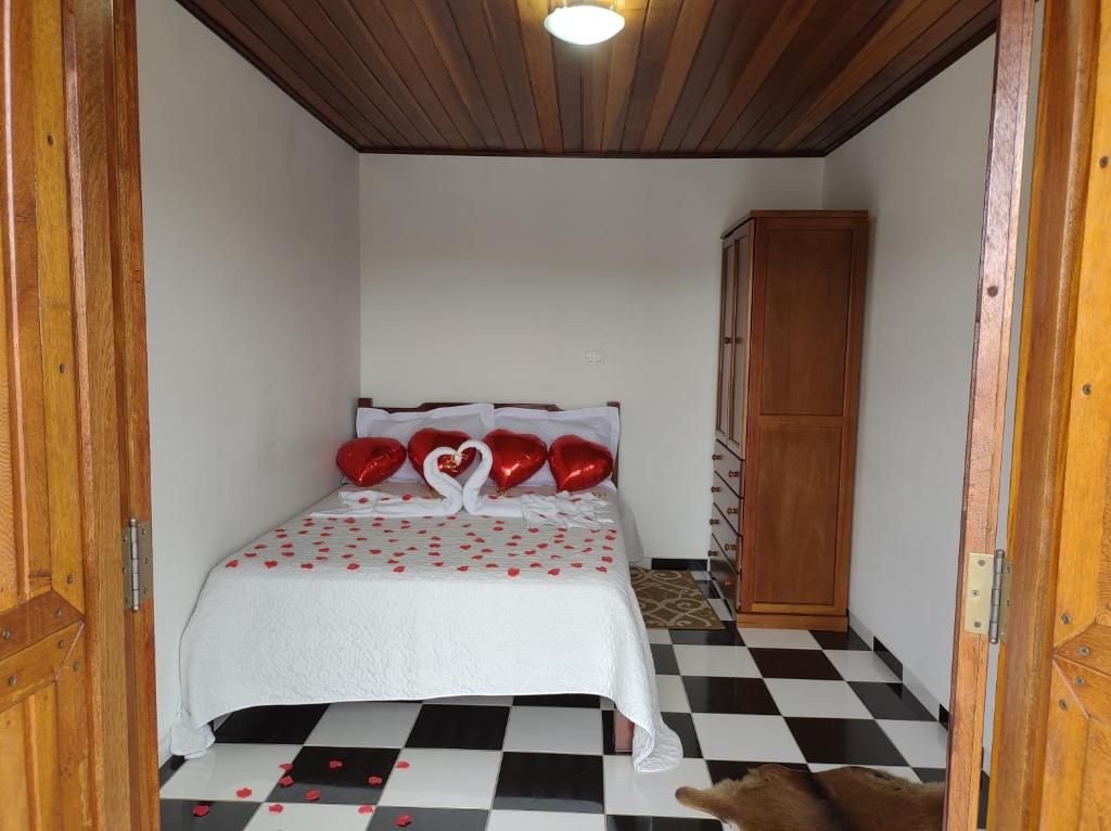 Flats Brancas Nuvens في كامبوس دو جورداو: غرفة نوم عليها سرير ومخدات حمراء