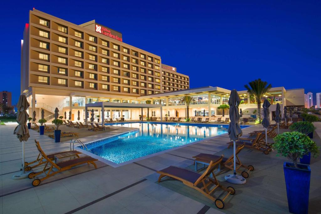 a hotel with a swimming pool at night at Hilton Garden Inn Ras Al Khaimah in Ras al Khaimah