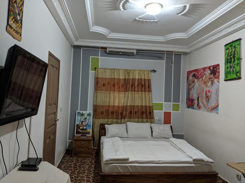 1 dormitorio con 1 cama y TV. en Hotel Bella Vida, en Lomé