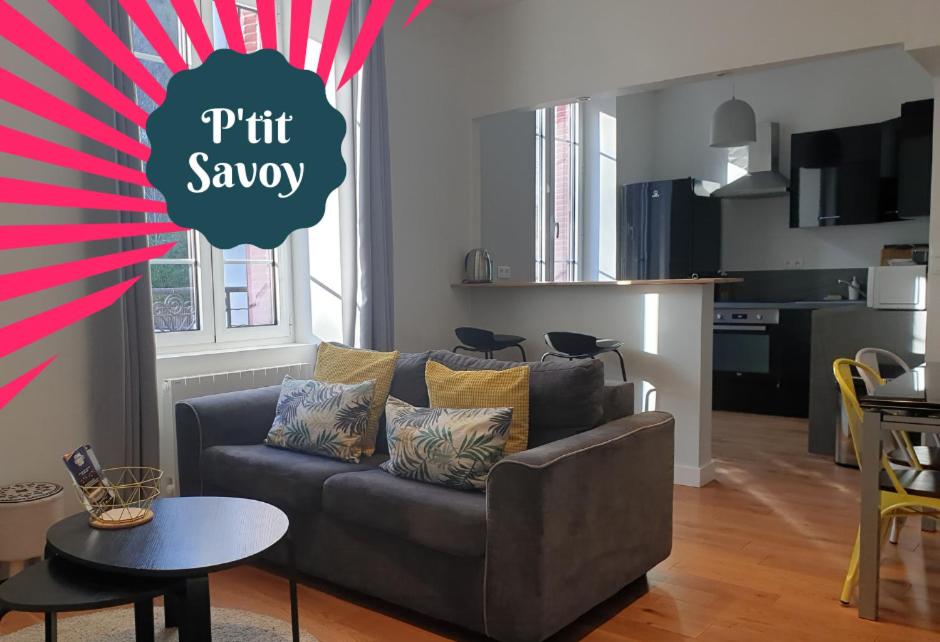 a living room with a couch and a kitchen at Ptit Savoy in Saint-Nectaire