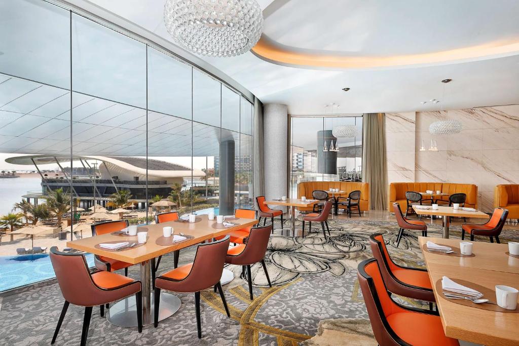a restaurant with tables and chairs and a pool at Conrad Abu Dhabi Etihad Towers in Abu Dhabi
