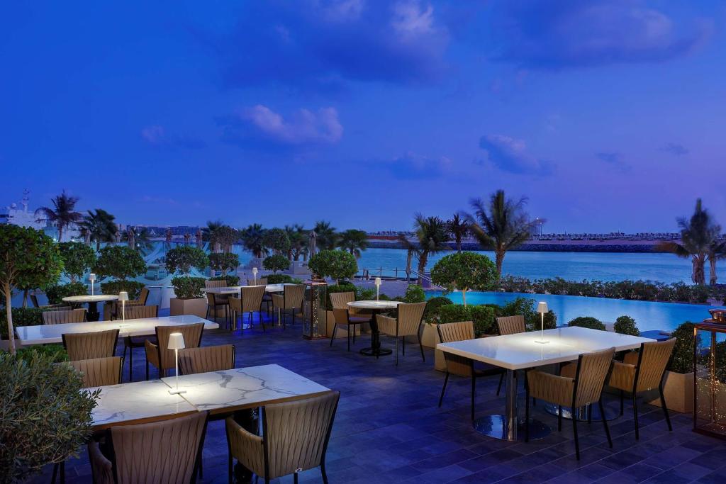 a restaurant with tables and chairs and a view of the water at Conrad Abu Dhabi Etihad Towers in Abu Dhabi