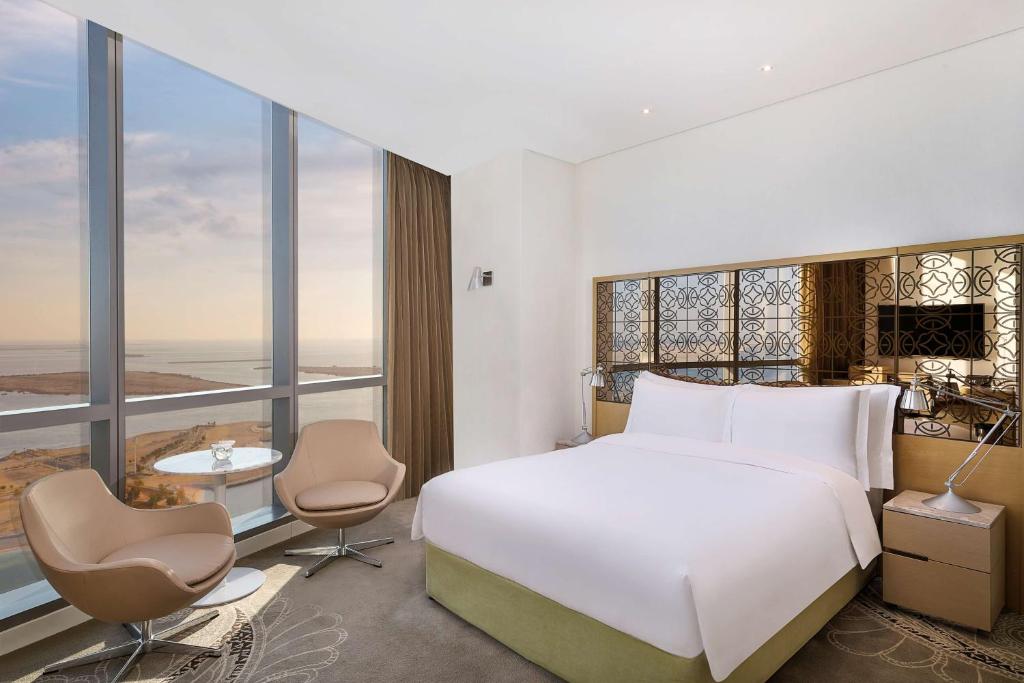 a bedroom with a white bed and a large window at Conrad Abu Dhabi Etihad Towers in Abu Dhabi