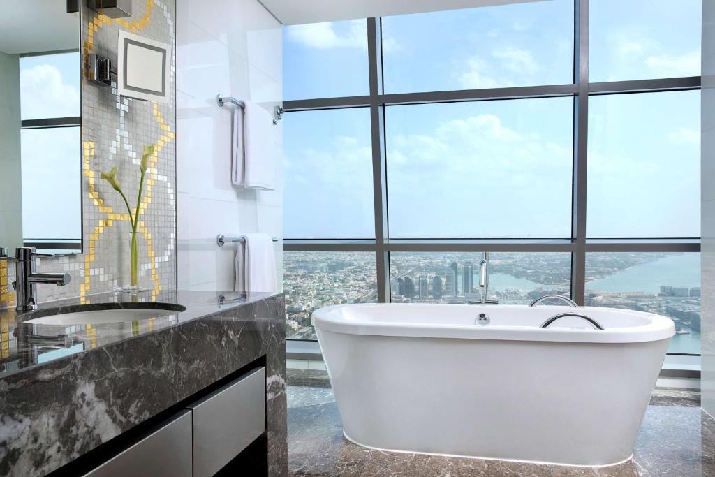 a bathroom with a large tub and a large window at Conrad Abu Dhabi Etihad Towers in Abu Dhabi