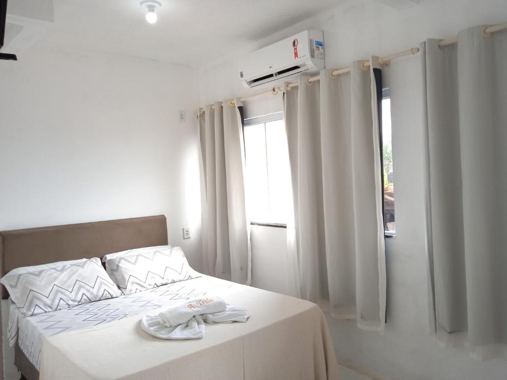 1 dormitorio con 1 cama con sábanas blancas y ventana en #Tribo Suítes no alto do morro, en Morro de São Paulo