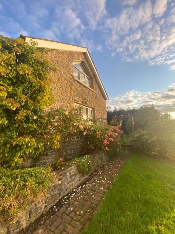 a brick house with flowers on the side of it at Pippin Lodge in Llanwrda