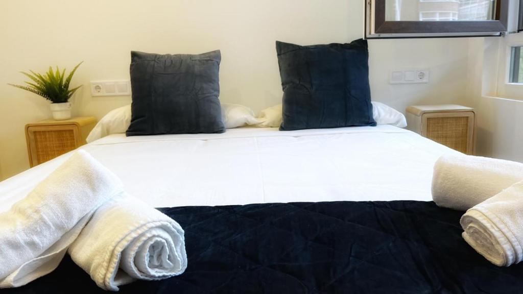 una camera da letto con un grande letto bianco con cuscini blu di Deustown Apartamentos a Bilbao