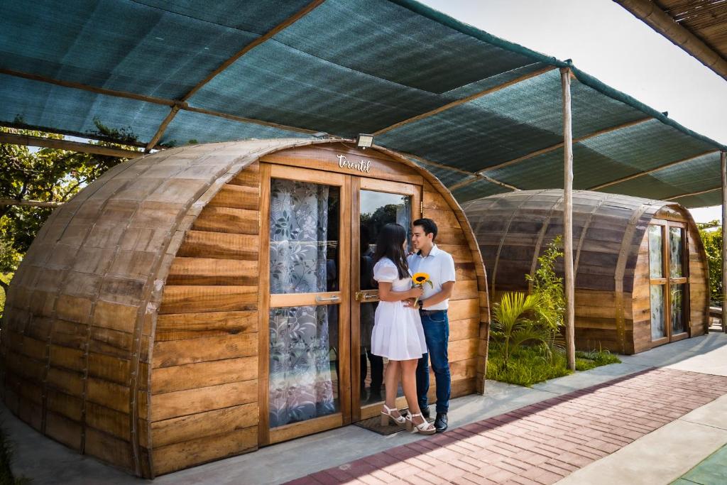 um casal em frente a uma casa de cúpula em GLAMPING TONELES Y VIÑEDOS em San Juan Bautista