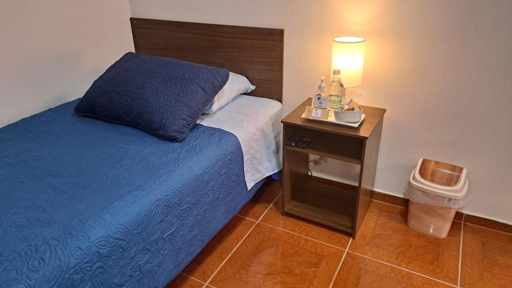 Residencial SOL NACIENTE في Pozo Almonte: غرفة نوم مع سرير و كومودينو مع غطاء سرير ازرق