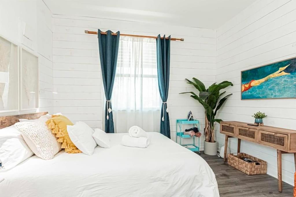 a bedroom with a white bed with blue curtains at Vanderbilt Beach Studio in Naples