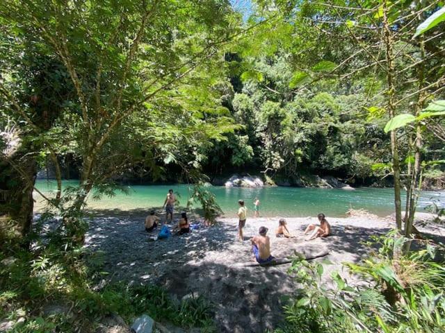 Un groupe de personnes assises sur le sable près d'une rivière dans l'établissement Refugio Natural Jacaranda CON PLAYA PRIVADA, à Cocorná