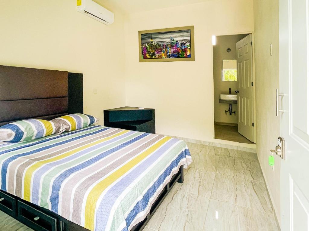 1 dormitorio con cama de rayas y baño en Hotel Vias Maya Bacalar en Bacalar