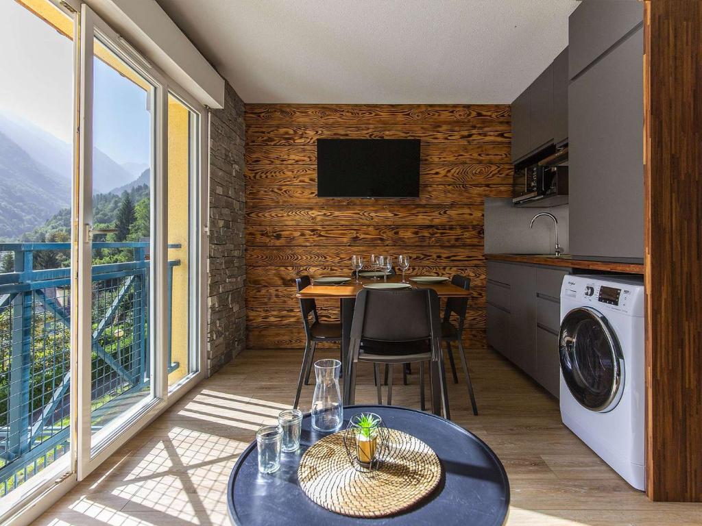 une cuisine et une salle à manger avec une table et un balcon dans l'établissement T2 rénové avec parking proche centre et télécabine - FR-1-401-267, à Cauterets