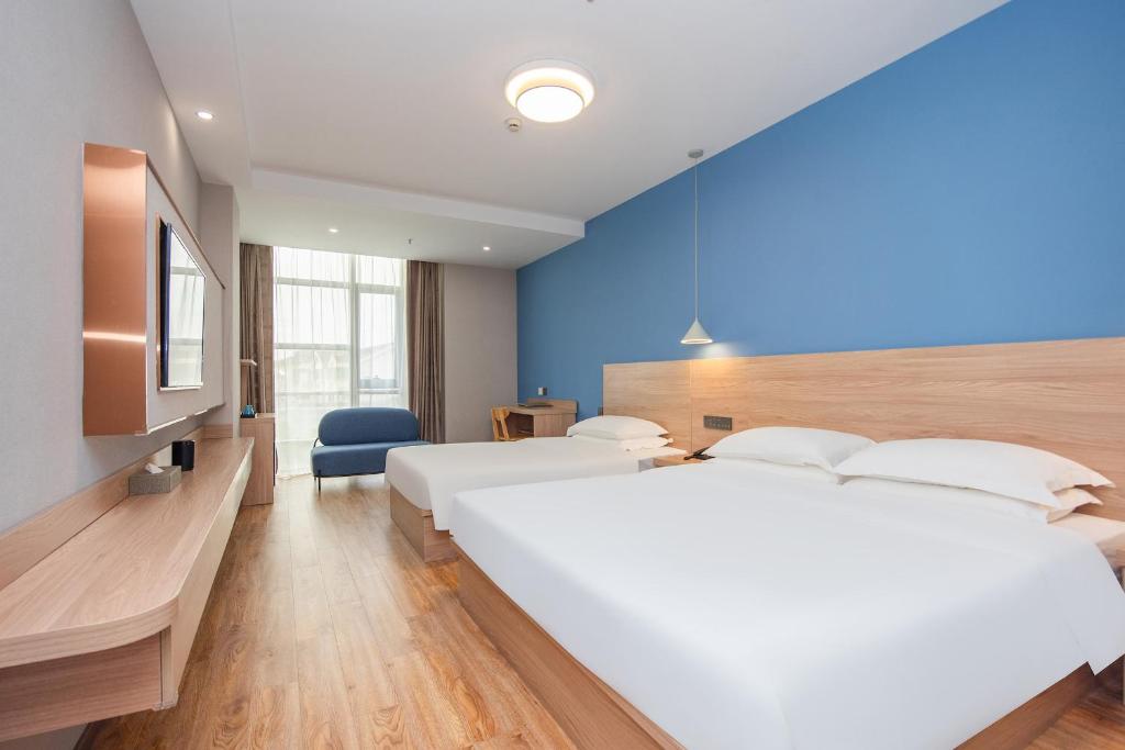 Future Shangju Hotel في شانغهاي: غرفة نوم بسريرين وجدار ازرق