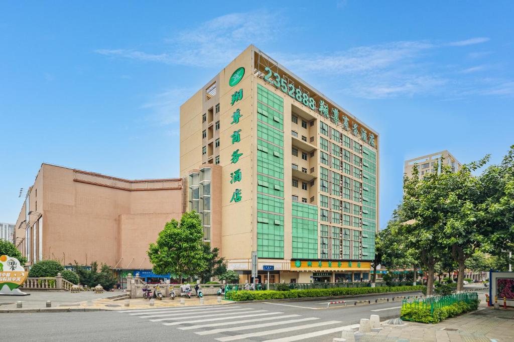 ein hohes Gebäude mit grünen Fenstern auf einer Stadtstraße in der Unterkunft Xiamen Xiangzun Hotel - Huijing Plaza Branch in Xiamen