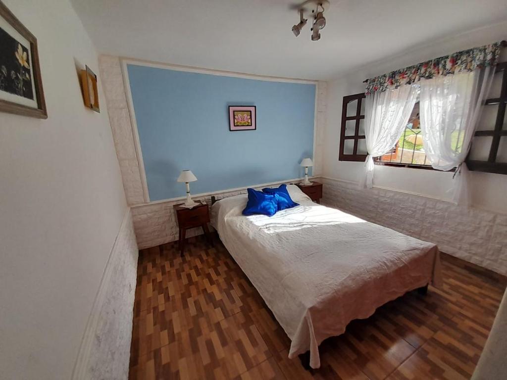 um quarto com uma cama com almofadas azuis e uma janela em cabaña alma dorada em Huerta Grande