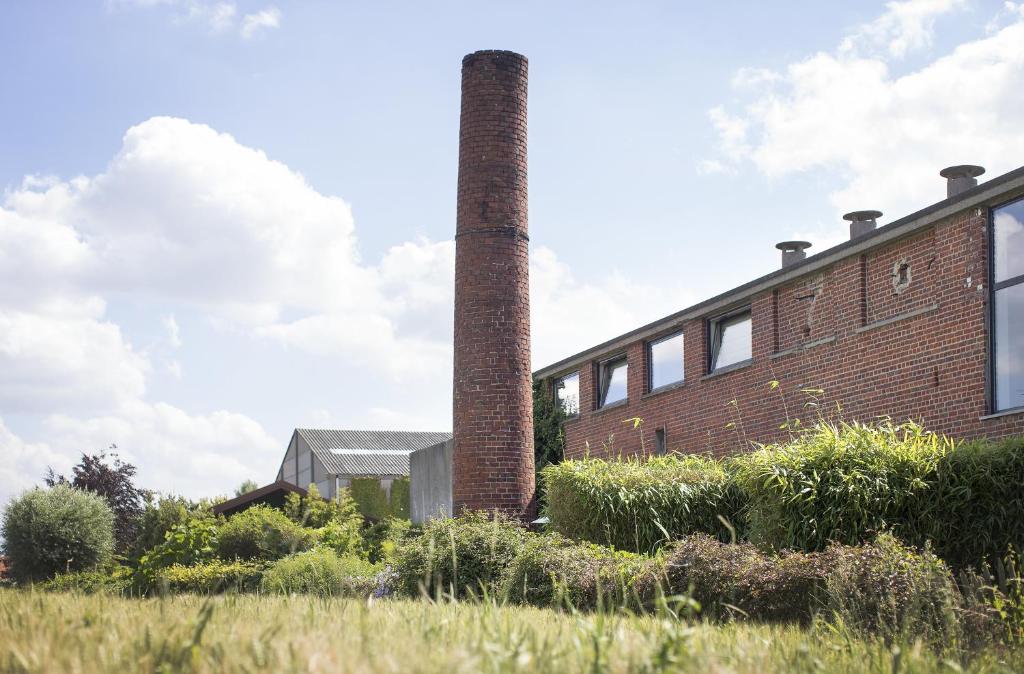 - un bâtiment en briques avec une cheminée sur le côté dans l'établissement B&B De Vlaschaerd, à Heule