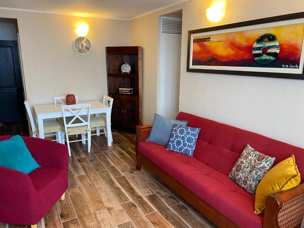 sala de estar con sofá rojo y mesa en Departamento Frente al Mar, Playa Bellavista, Tome, en Tomé