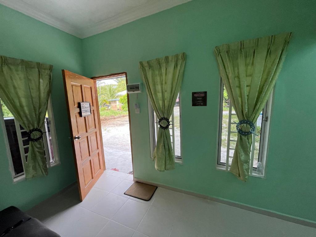 ein grünes Zimmer mit einer Tür und zwei Fenstern in der Unterkunft Rumah Comel in Kampung Degong