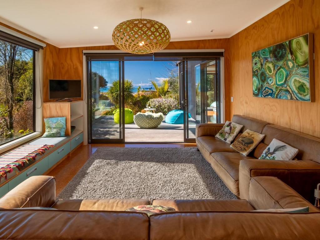 sala de estar con sofá y ventana grande en Bach 7 by The Sea - Marahau Holiday Home, en Marahau