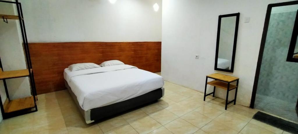 um quarto com uma cama branca e um espelho em HER MANDIRI GUEST HOUSE em Balikpapan